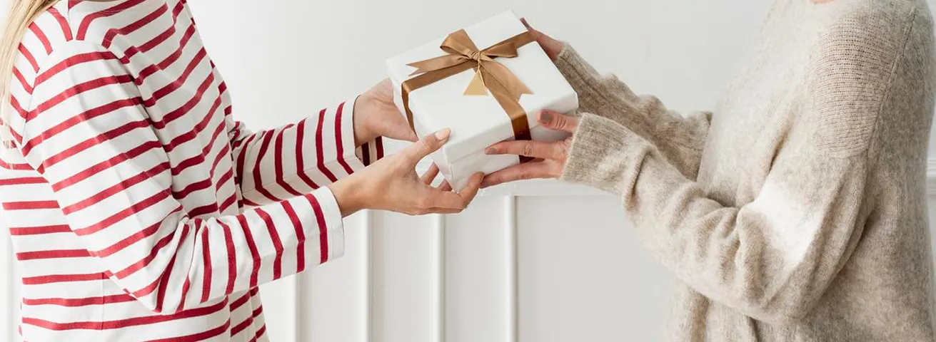 Zwei Menschen überreichen ein verpacktes Geschenk